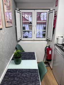 a small kitchen with a table and two windows at coração alfama in Lisbon