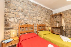 a bedroom with two beds and a stone wall at Climbing House in Baunei