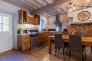 a kitchen with a wooden table and a clock on the wall at Montauvert in Montel-de-Gelat