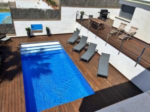 a swimming pool with chairs and a table on a deck at R64 Deluxe Villa Déjà Vu in Calafell