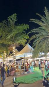 a group of people walking around a market with palm trees at Sanctuary by JVS Palace in Hindupur