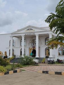 a white building with a car parked in front of it at Sanctuary by JVS Palace in Hindupur