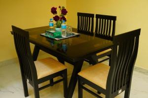 a dining room table with two chairs and flowers on it at YELAGiRI GRAND PALACE in Yelagiri