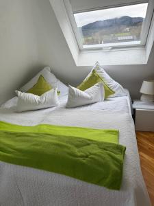 ein weißes Bett mit grünen Laken und ein Fenster in der Unterkunft MarijaM-Haus in Badenweiler