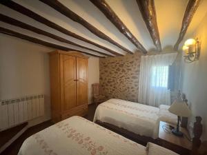 a bedroom with two beds and a cabinet and a window at Casa Rural Vicenta in Benizar