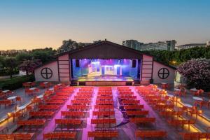 a large auditorium with red chairs and a stage at Limak Lara Deluxe Hotel & Resort Antalya in Lara +103 photos