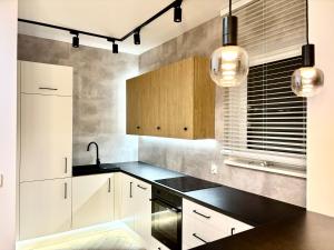 a kitchen with white cabinets and black counter tops at Apartament Kaszubska Bryza III - HEL in Hel