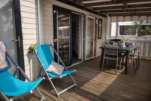 a screened porch with a table and chairs on it at ZEcamping 4 étoiles animé piscine couverte 1km plage fitness mobil-home TV in Saint-Jean-de-Monts