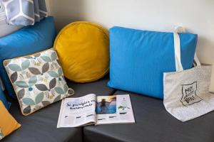 a blue couch with two bags and a book at ZEcamping 4 étoiles animé piscine couverte 1km plage fitness mobil-home TV in Saint-Jean-de-Monts