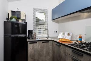 a kitchen with a black refrigerator and a sink at ZEcamping 4 étoiles animé piscine couverte 1km plage fitness mobil-home TV in Saint-Jean-de-Monts