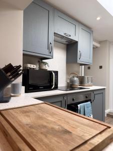 a kitchen with blue cabinets and a black microwave at Sandytoes Cottage in Pentraeth