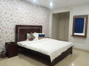 a bedroom with a bed with white sheets and floral wallpaper at Hotel Marvi Multan in Multan +8 photos