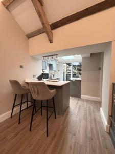a kitchen with a counter and two stools at Sandytoes Cottage in Pentraeth +17 photos