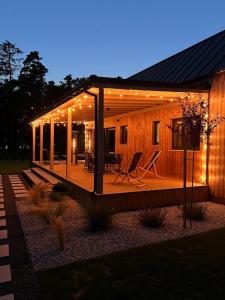 a house with a deck with lights on it at Forrestia - osada turystyczna in Czaplinek