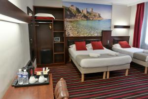 a bedroom with two beds and a large painting on the wall at Hotel De L'univers in Saint Malo