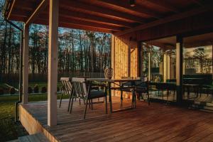 a wooden deck with a table and chairs on it at Forrestia - osada turystyczna in Czaplinek +78 photos