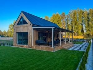 a small house with a roof on a lawn at Forrestia - osada turystyczna in Czaplinek