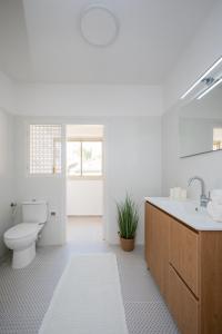 a white bathroom with a toilet and a sink at R26-Boutique in Zikhron Ya'akov