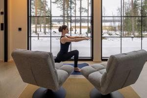 a woman doing a yoga pose in front of a window at New Seaside Villa with Beach Sauna and Panoramic Views in Porvoo