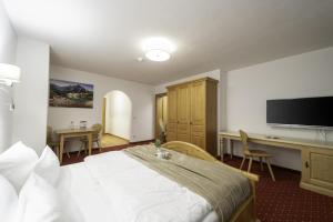 a hotel room with a bed and a desk and a television at Hotel ZUM STERNENHOF in Kössen