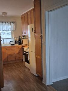 a kitchen with a white refrigerator and wooden cabinets at House by Ramberg Beach in Ramberg