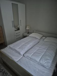 a bedroom with a bed with white sheets and a mirror at House by Ramberg Beach in Ramberg
