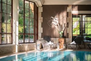 an indoor pool with a chair and windows at Hotel ZUM STERNENHOF in Kössen