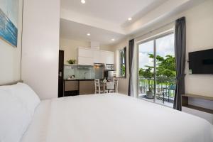 a bedroom with a white bed and a kitchen at F-APARTMENT in Ho Chi Minh City
