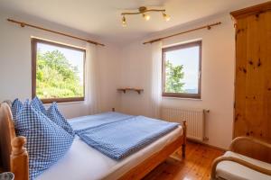 a bedroom with a bed and two windows at Wabnig- der Logenplatz in der Natur in Moosburg