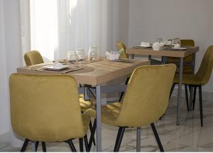 a dining room table with yellow chairs and a wooden table at Augustea Travel Rooms in Frignano
