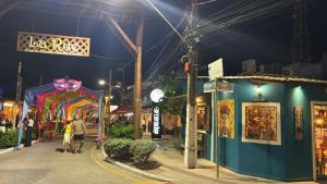 a street at night with people walking down the street at Sol, mar, equilíbrio perfeito praia do frances! in Marechal Deodoro