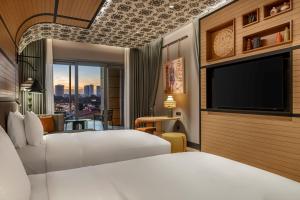a hotel room with two beds and a flat screen tv at Canopy By Hilton Izmir Bomonti in İzmir
