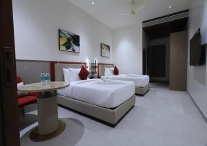 a hotel room with two beds and a table at Antra Luxe in Anumalkudūru
