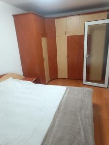 a bedroom with a white bed and wooden cabinets at Apart Robert 1 in Bicaz