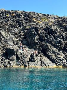 a group of people on a rocky hill with the water at Attico La Navicella in Pantelleria +1 photo