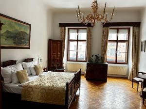 a bedroom with a bed and a chandelier and windows at Grand Hotel Praha in Prague