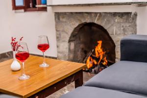 two glasses of red wine sitting on a table in front of a fireplace at Tripp Jim Corbett A River Access Resort in Marchula