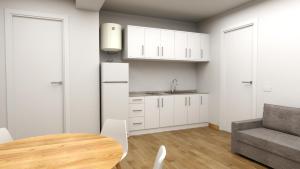 a kitchen with white cabinets and a table and a couch at Climia 2Sleep Apartments in Benidorm