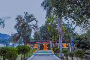 a house with palm trees in front of it at Tripp Jim Corbett A River Access Resort in Marchula