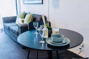 a black coffee table with plates and wine glasses at 1 Bedroom Apartment In the heart of Parramatta CBD in Sydney