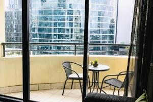 a table and chairs on a balcony with a view of a city at 1 Bedroom Apartment In the heart of Parramatta CBD in Sydney