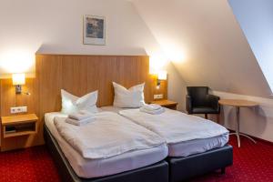 a hotel room with a large bed with white sheets at Pension Krone in Schwäbisch Gmünd