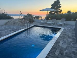 a swimming pool with two chairs and an umbrella at Top5 in Baška Voda