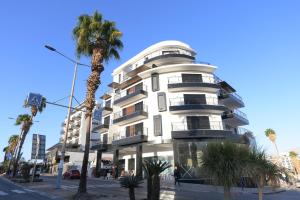 a white building with palm trees in front of it at Cohav Sea View in Eilat