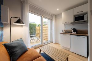 a living room with a couch and a kitchen with a window at Air Nomad • Sydney in Valenciennes