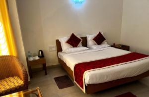 a bedroom with a bed with pillows and a chair at KSTDC Hotel Mayura Sangama Mekedatu in Mulhalli +25 photos