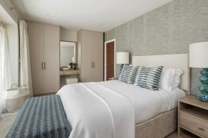 a bedroom with a large white bed with blue pillows at Hill View House - Cookswood in Holcombe