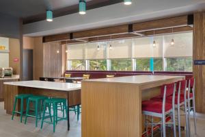 a restaurant with a bar with green stools at Tru By Hilton Gananoque, On in Gananoque