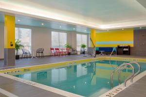 a pool in a hotel room with chairs and tables at Tru By Hilton Gananoque, On in Gananoque