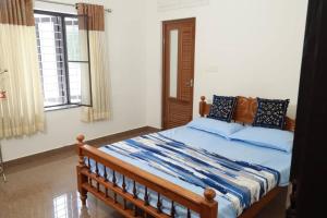 a bedroom with a bed with blue sheets and windows at Well maintained Calm atmosphere in Putuppalli